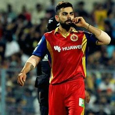 a man with a beard standing in front of a crowd wearing a red and yellow uniform