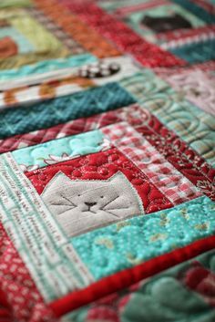 a close up view of a quilt with a cat on it's side and a crochet hook in the middle