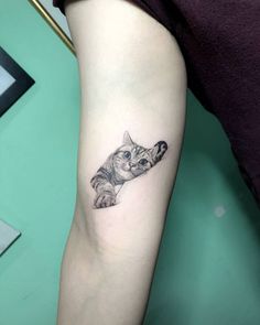 a small cat tattoo on the left inner arm and leg, with one paw in the air