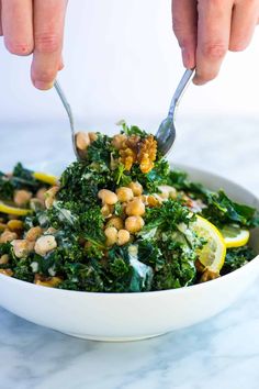 a person is spooning some food out of a bowl with broccoli and chickpeas