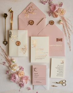 the wedding stationery is laid out with pink flowers and gold foil stamping on it