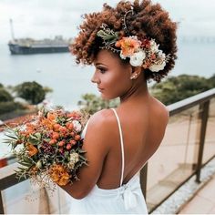 a woman with flowers in her hair is standing on a balcony looking at the water