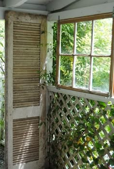 an open window in the corner of a room next to a wooden fence with vines growing on it