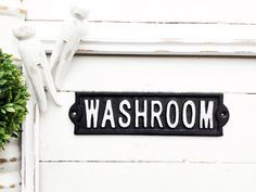 a black and white sign that says washroom next to a potted green plant