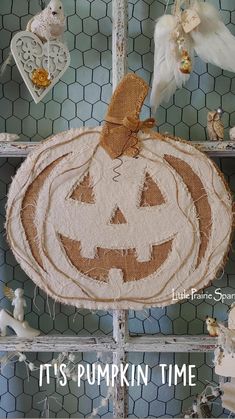 a pumpkin shaped door hanger on a chicken wire fence with other decorations around it