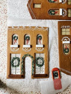 gingerbread houses decorated with christmas wreaths and decorations on top of a white tablecloth