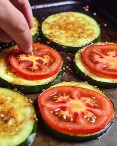 someone is placing tomatoes on top of zucchini