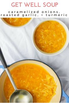 two bowls filled with carrot soup on top of a white table cloth next to silver spoons