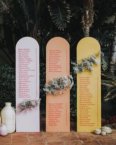 three wooden signs with names on them sitting next to flowers and vases in front of trees