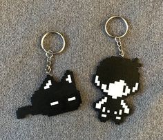 two black and white pixelated keychains sitting on top of a gray carpet