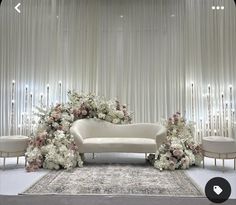 a white couch sitting on top of a rug in front of a wall covered in flowers