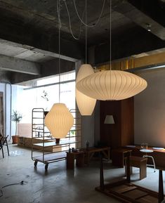 three lamps hanging from the ceiling in an office space with wooden tables and stools