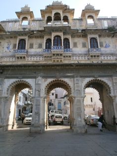 an old building with arches and cars parked in front