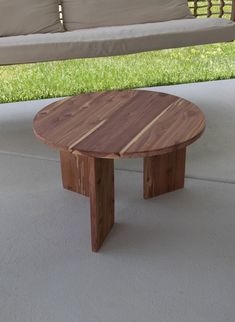 a wooden table sitting on top of a cement floor next to a bench and grass