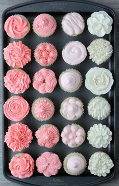 cupcakes with pink and white frosting are arranged in a baking tray on a table