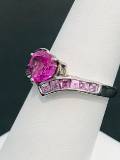 This striking heart shape pink cubic zirconia ring is handmade in sterling silver and is complete with princess cut light powder pink cubic zirconias and two natural white diamond accents. The vibrancy of the center stone will make your mouth water! The design was meticulously thought out as it includes two hearts on each side of the ring in filigree metal work. Can be sized up or down for an additional charge. Feel free to contact us with any questions you may have. Fine Jewelry With Cubic Zirconia And Side Stones, Dazzling Pink Sterling Silver Ring, Pink Birthstone Promise Ring In Fine Jewelry Style, Fine Jewelry Rings With Side Stones As Gift, Pink Cubic Zirconia Fine Jewelry Ring, Fine Jewelry Heart Cut Pink Jewelry, Pink Gemstone Promise Birthstone Ring, Heart-shaped Pink Jewelry With Diamond Accents, Pink Birthstone Promise Ring With Gemstone