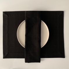 a white plate and black napkin sitting on top of a table