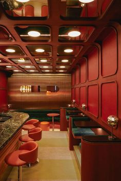 the interior of a restaurant with red walls and bar stools