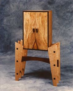 a wooden chair with two legs and a cabinet on the back that has holes in it