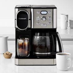 a coffee maker sitting on top of a counter next to a cup and saucer