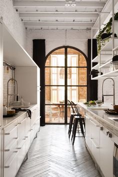 an open kitchen with white cabinets and wooden floors