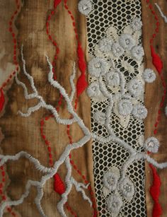 an embroidered piece of cloth with red and white flowers on the edges, sitting on a wooden surface