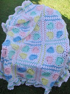 a crocheted blanket is laying on the grass