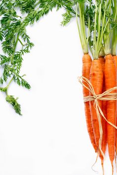 three carrots tied up with twine and green leaves on white background, top view