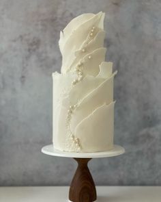 a white wedding cake on a wooden stand