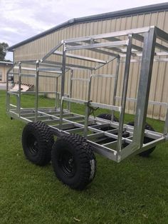 a trailer that is on some grass in front of a building with two large tires