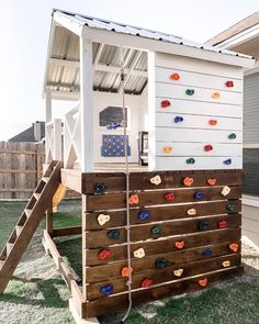 an outdoor play structure made out of pallet wood and painted white with colorful rocks on the side