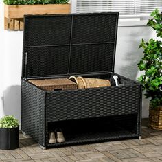 an outdoor storage box with two baskets on the bottom and one open, sitting next to a potted plant