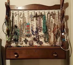 a wooden shelf with lots of necklaces on it