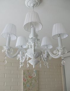 a white chandelier hanging from the ceiling in a room with two lamps on either side