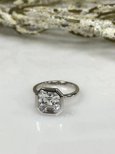 a diamond ring sitting on top of a white table next to a rock and stone