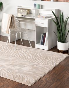 a white desk sitting on top of a wooden floor next to a potted plant