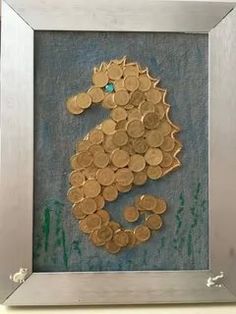 a seahorse made out of gold coins in a silver frame on a table top