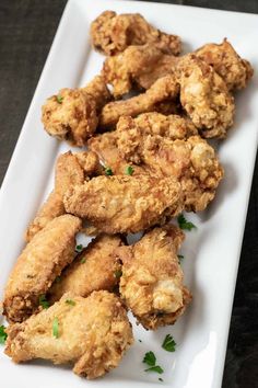 fried chicken on a white plate with parsley sprinkled around the edges, ready to be eaten