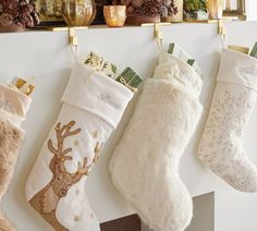 three christmas stockings hanging on a mantle with candles and other holiday decorations in the background