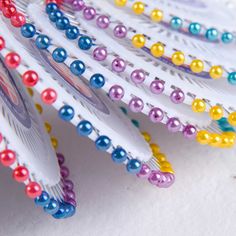 several multicolored toothbrushes are lined up on a white surface with colorful beads