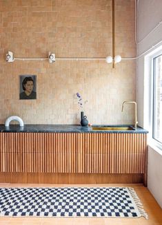 a kitchen with a checkered rug and wooden cabinets on the wall next to a window