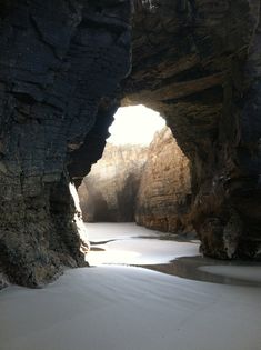 the sun shines through an opening in a rock formation, which is partially covered by snow