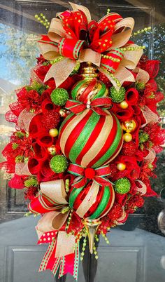 a christmas wreath with red, green and gold ornaments hanging on the front door ornament