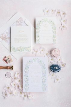 the wedding stationery is laid out on top of each other, including an envelope and ring