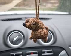 a crocheted dog hanging from the dashboard of a car ornament on a steering wheel