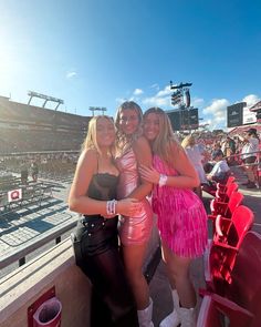 two women in pink dresses standing next to each other at a baseball game with fans