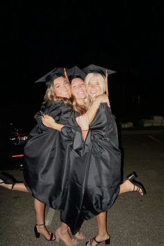 three women in graduation gowns hugging each other