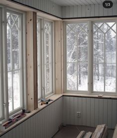 an empty room with three windows and some boards on the floor in front of them