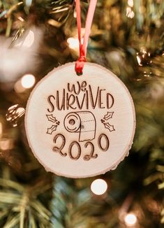 a wooden ornament hanging from a christmas tree with the words survived on it