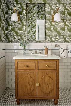 a bathroom with green and white wallpaper, two sinks and a large mirror on the wall